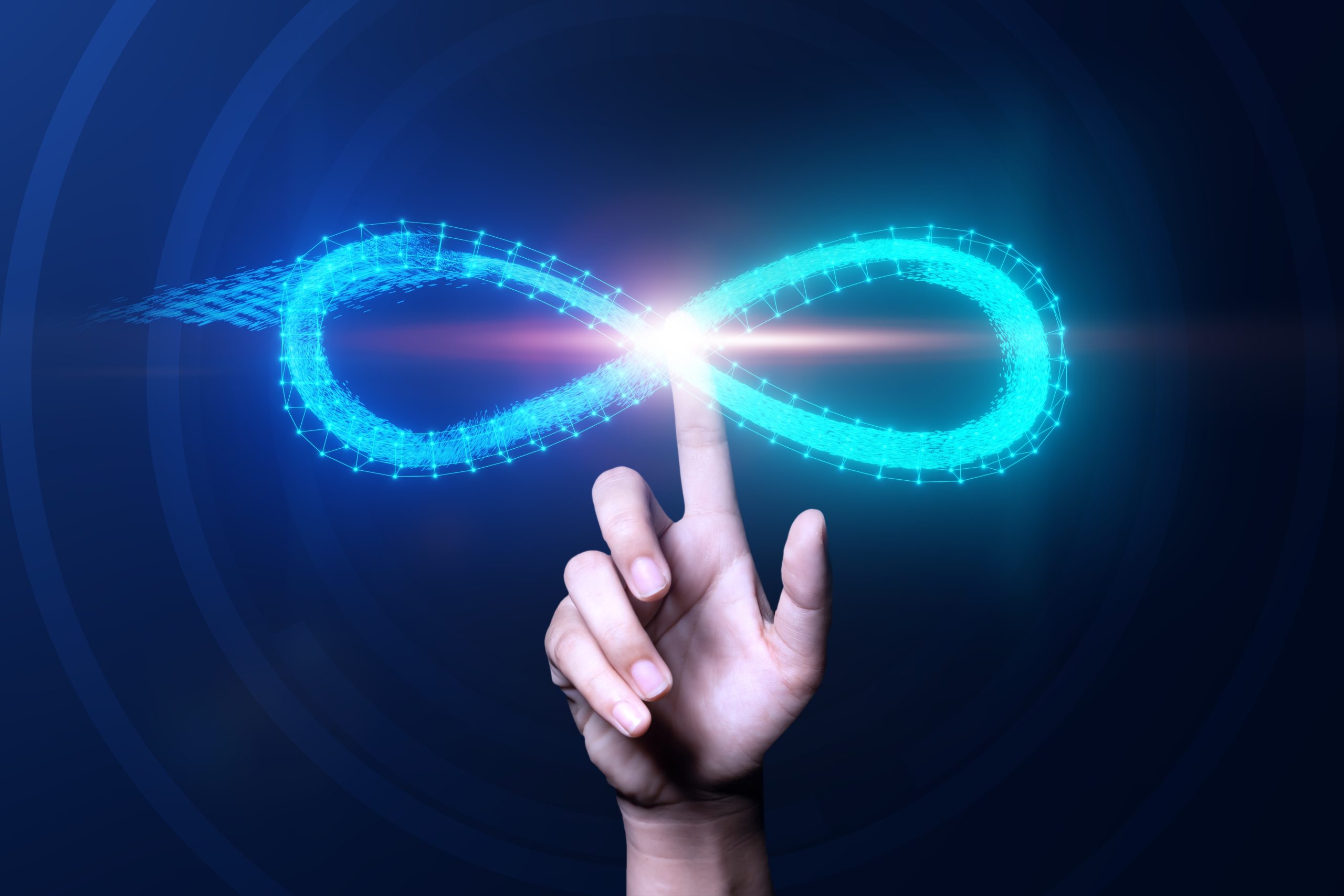 A hand with an outstretched index finger touches the center of a glowing blue infinity symbol, set against a dark background. Light radiates from where the finger meets the symbol.